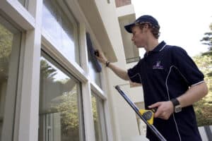Professional window cleaner wiping the interior glass of a window